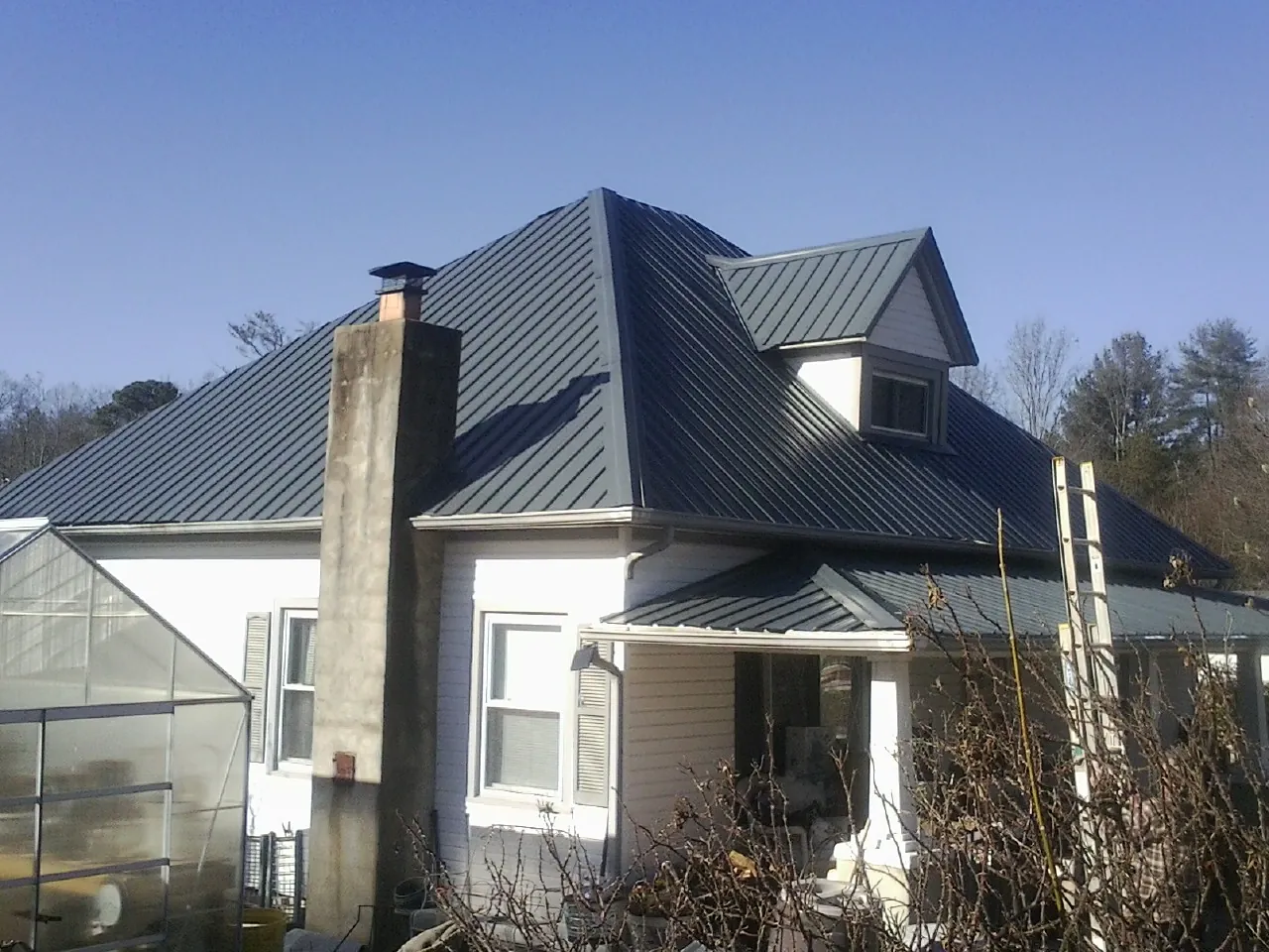 Dark blue standing seam metal roof on a white farmhouse with dormer — Slate & Tile Roof Repair by Roofing Brothers in Woodberry Forest