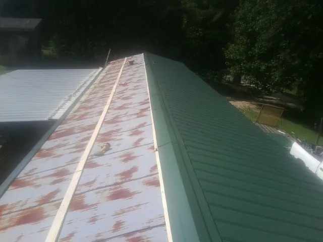 Old rusted panels beside newly installed green metal roofing — Wind Damage Roof Repair by Roofing Brothers in Woodberry Forest