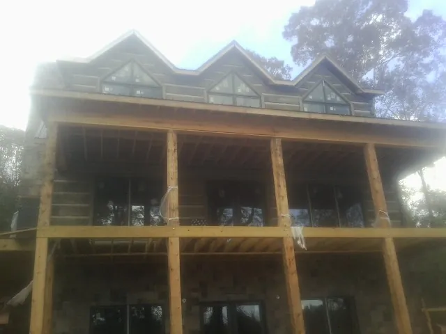 Dormers and porch framing on a large log home under construction — Roof Coating work by our crew in Woodberry Forest