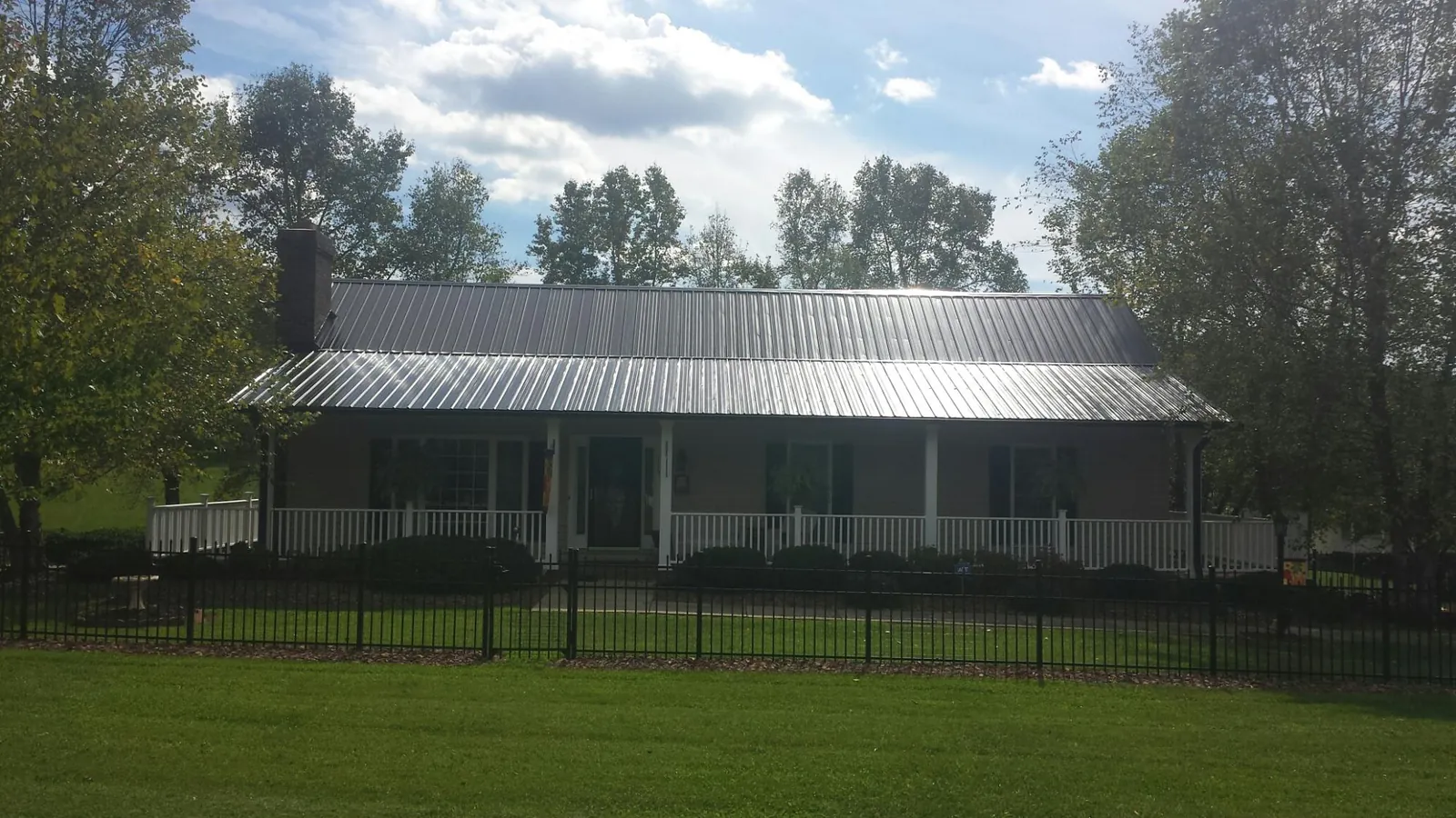 Gray metal roof on a brick ranch with a full width front porch — Gutter Guard Installation work by our crew in Woodberry Forest