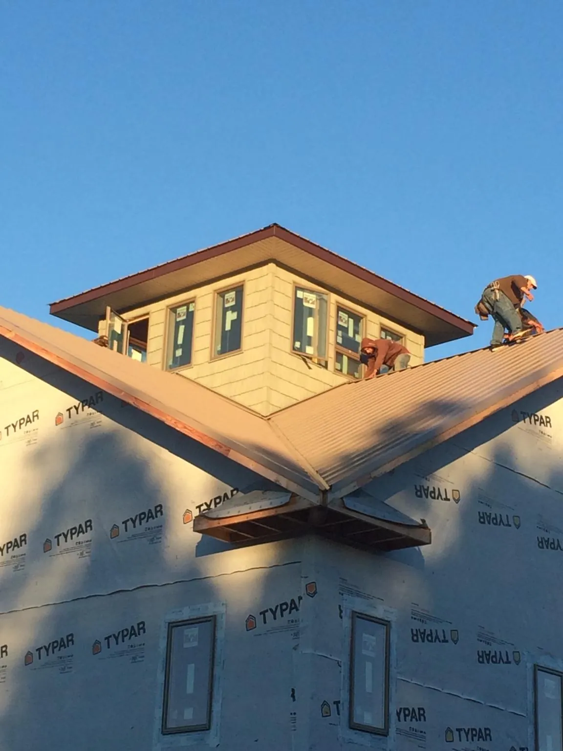 Roofers working around a rooftop cupola on a new metal roof at sunset — Roof Waterproofing in Woodberry Forest by Roofing Brothers